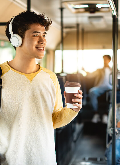 Young man traveling by bus with coffee and headphones