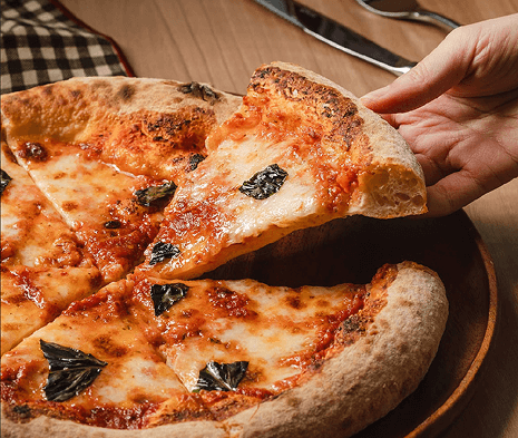 Hand pulling a slice of margherita pizza